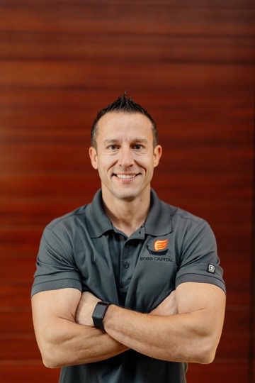 A man with his arms crossed standing in front of a wall.